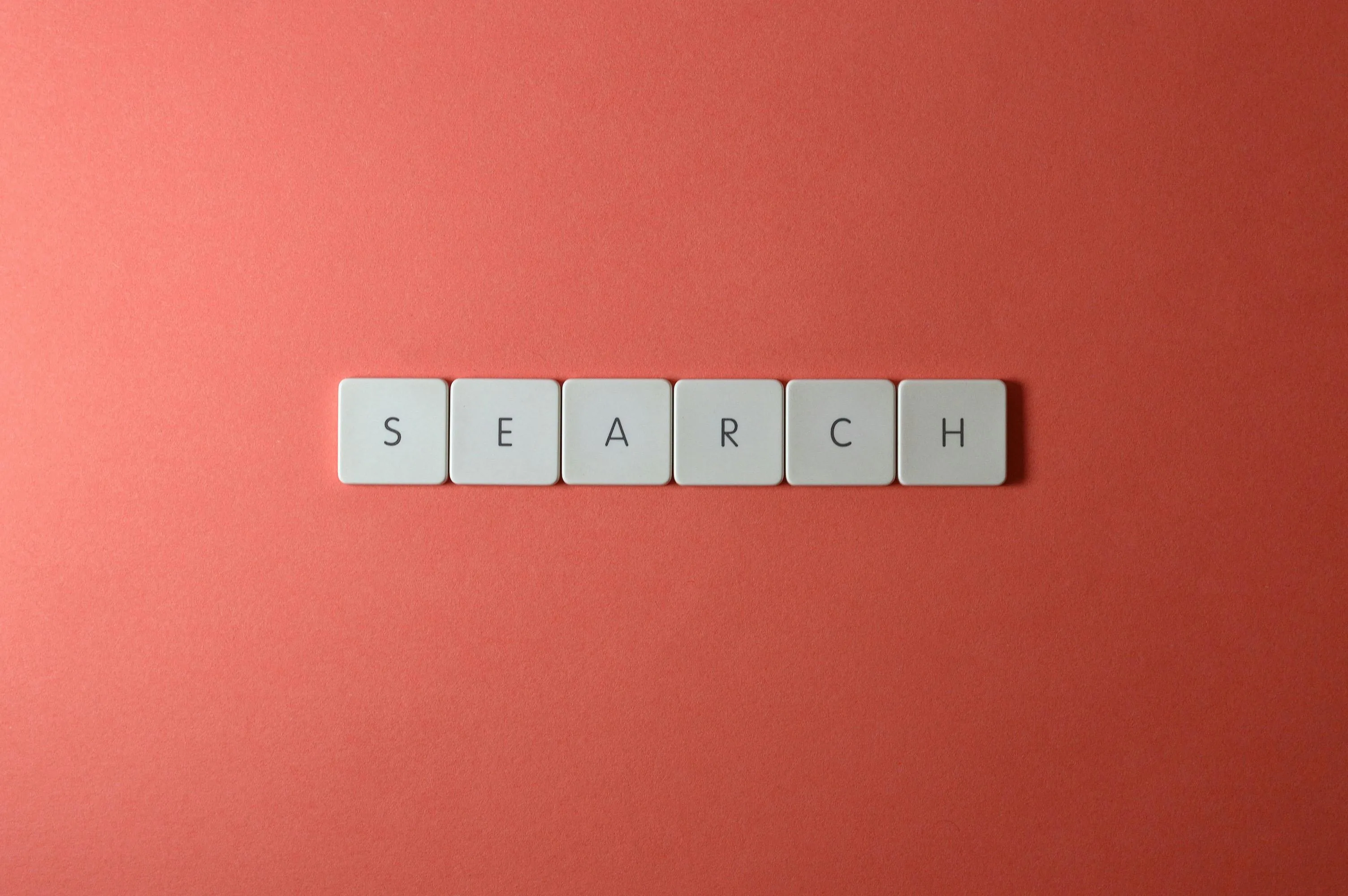 Teclado blanco con teclas que forman la palabra search sobre fondo rojo ilustrando la nueva guía oficial de Google AI Overviews
